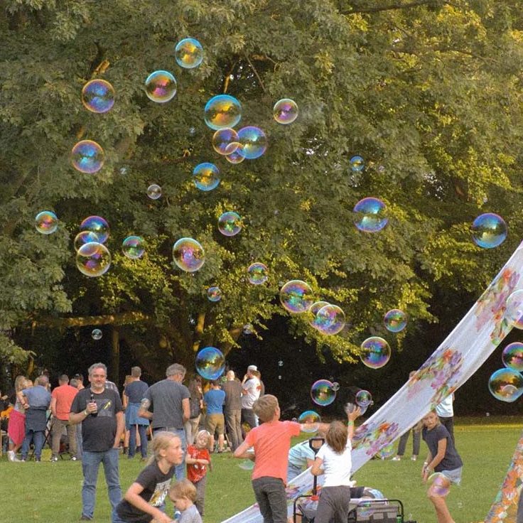 Kinderen spelen en lachen in een park terwijl zeepbellen door de lucht zweven.